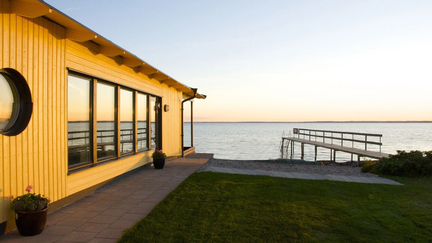 Utsikt mot ett stilla sund på Råå Kallbadhus, en brygga leder ut en bit i havet.