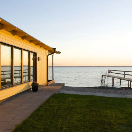 Utsikt mot ett stilla sund på Råå Kallbadhus, en brygga leder ut en bit i havet.