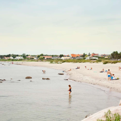 Bad på stranden i Domsten, villor skymtar i bakgrunden.