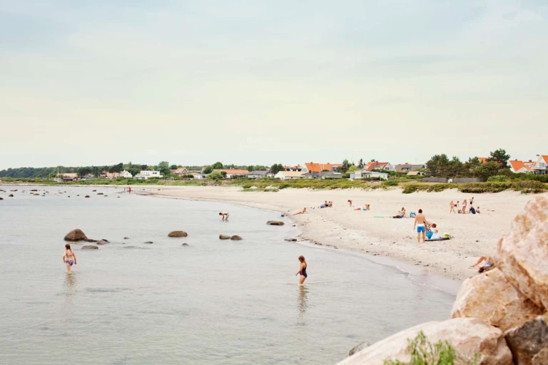 Bad på stranden i Domsten, villor skymtar i bakgrunden.