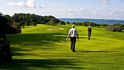 Två golfspelare på Rya golfbana med utsikt över Sundet.