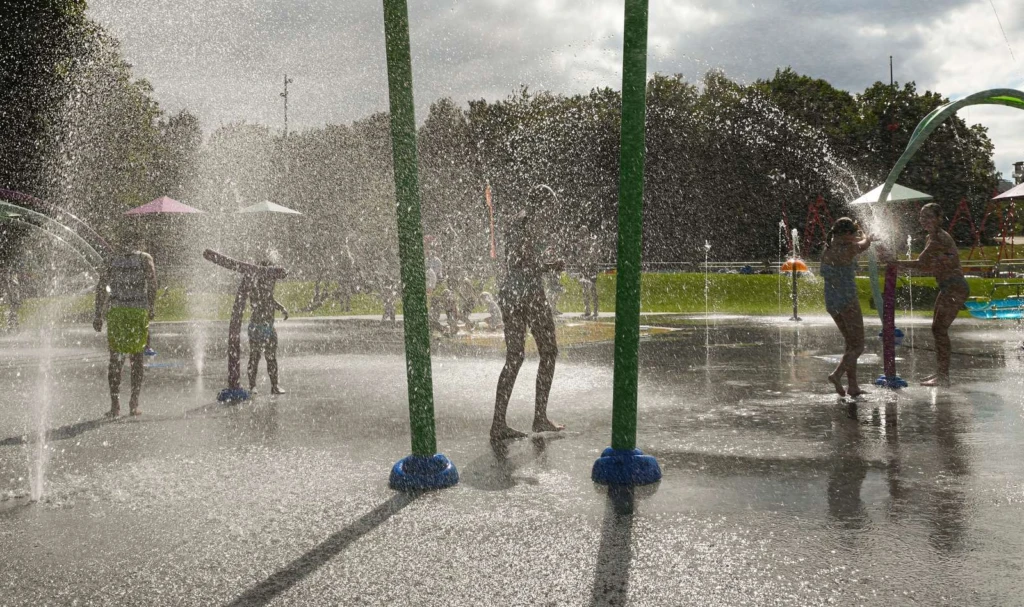 vattenlekplats med lekande barn och sprutande vatten