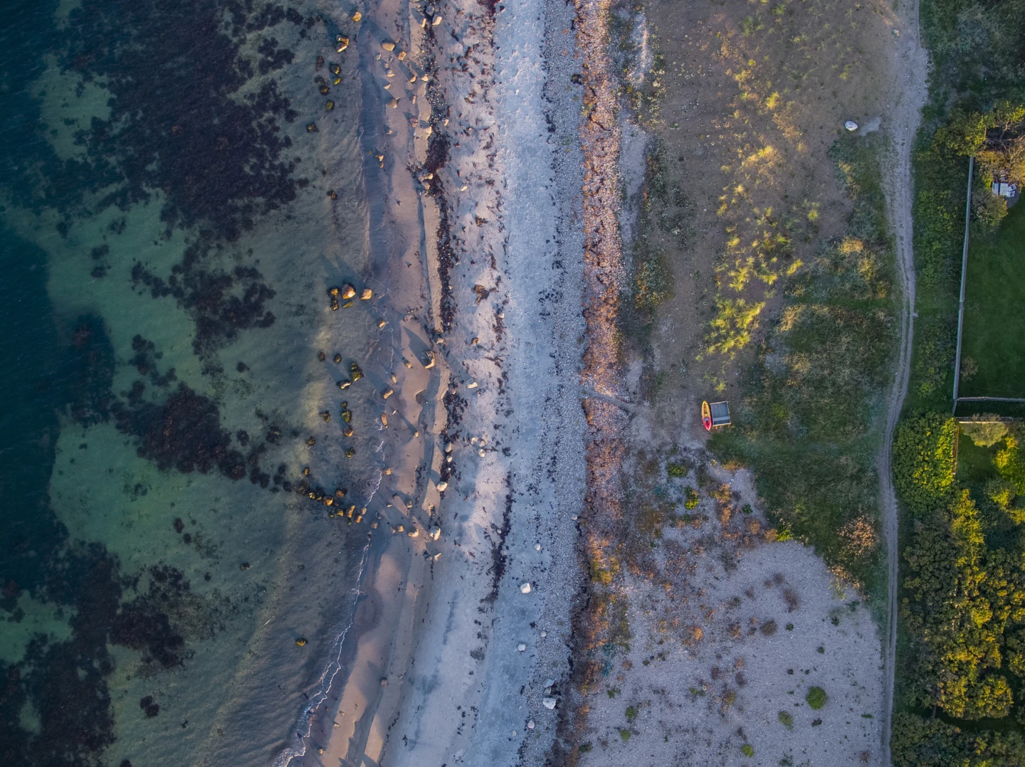 Vacker kustlinje längs kullaleden utanför Helsingborg. Turkost vatten och längs stranden går en smal stig.