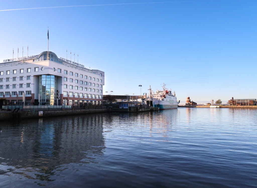 Vy över hotell Marina Plaza från kajkanten med hamnbassängen framför.