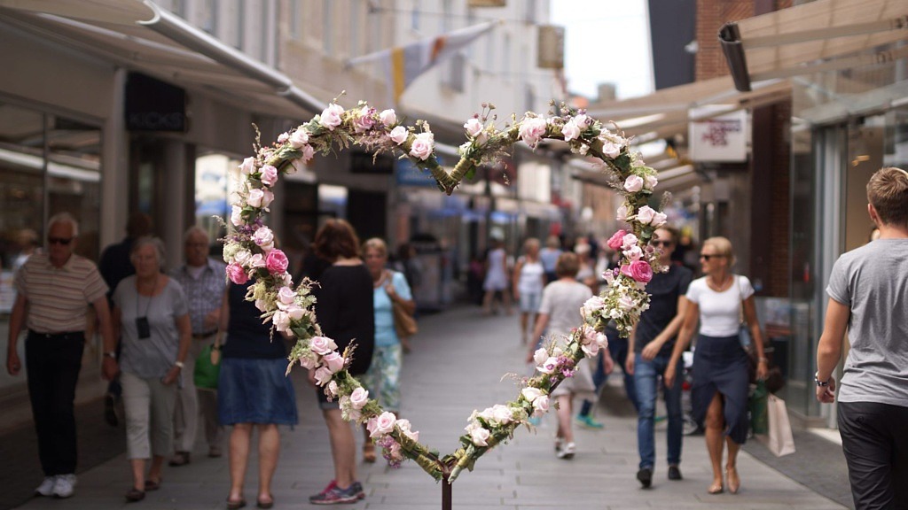 Ett hjärta av blommor mitt på Kullagatan med sommarklädda människor på gatan