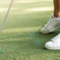 Närbild på minigolfbana med en persons om håller i en klubba med rosa boll.