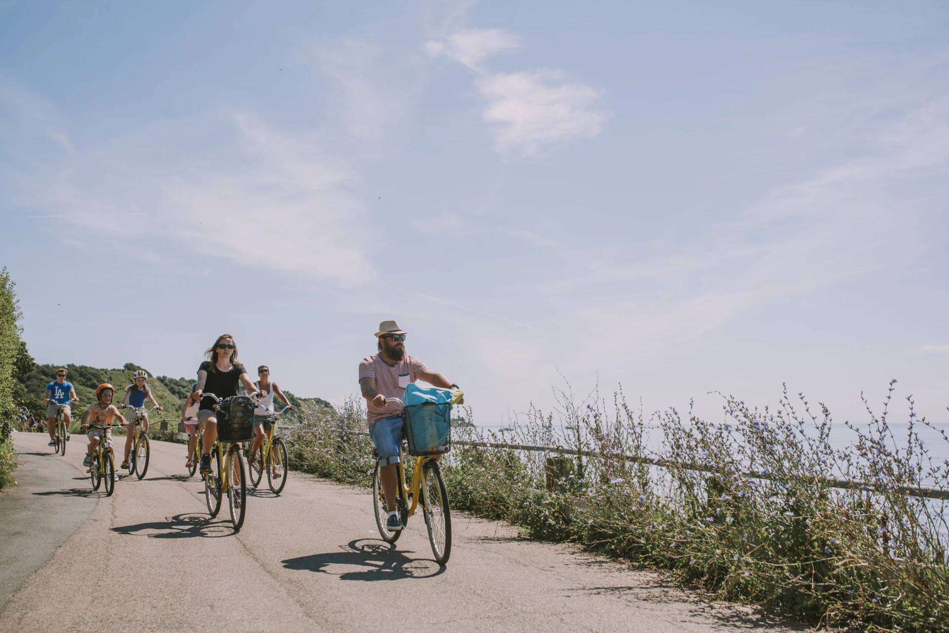 Flera cyklister på ön ven längs en mindre väg precis vid havet. Sommarkänsla