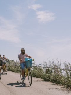 Flera cyklister på ön ven längs en mindre väg precis vid havet. Sommarkänsla
