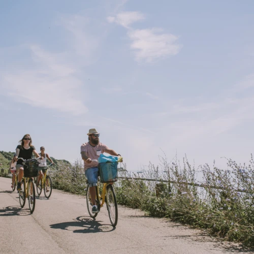 Flera cyklister på ön ven längs en mindre väg precis vid havet. Sommarkänsla