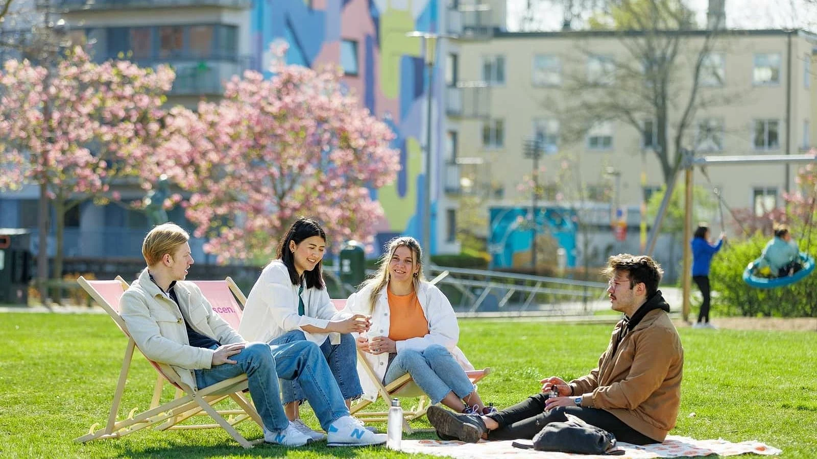 studenter hänger i en park med körsbärsträd i blom.