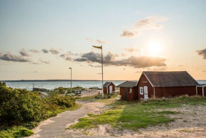 Två fiskebodar vid stranden i Domsten. Kvällsljus.