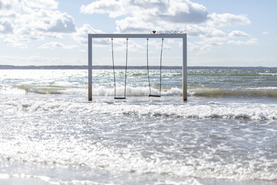 En gungställning en bit ut i havet med två gungor. Uppe på ställning finns ett hjärta och texten Helsingborg.