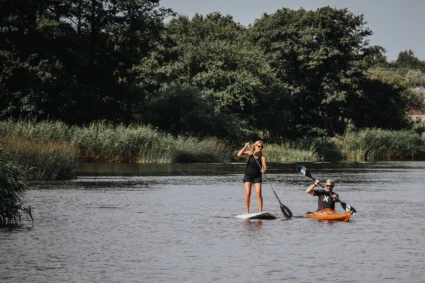 Två personer paddlar kajak och sup på Rönneå.