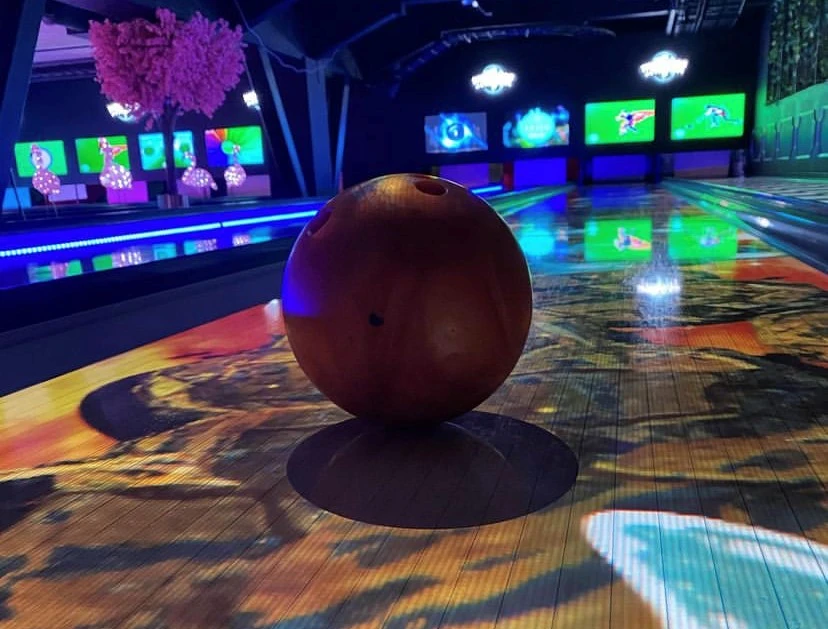En bild med ett bowlingklot i centrum med discokänsla.
