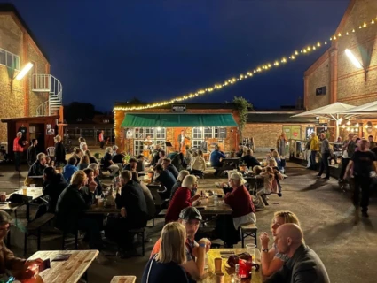 sommarkväll och en ett folkhav av personer som sitter vid bänka och bord på en festival