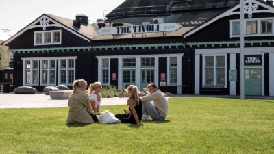 Fyra personer sitter på en gräsmatta framför The Tivoli.