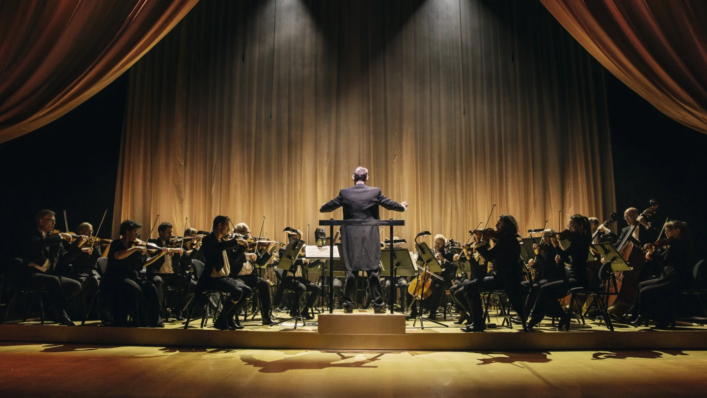 Orkester spelar klassisk musik en en upplyst scen