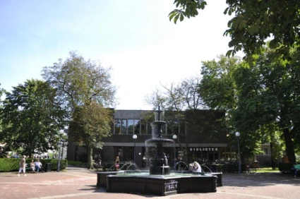 Fontän i förgrunden framför ett bibliotek.