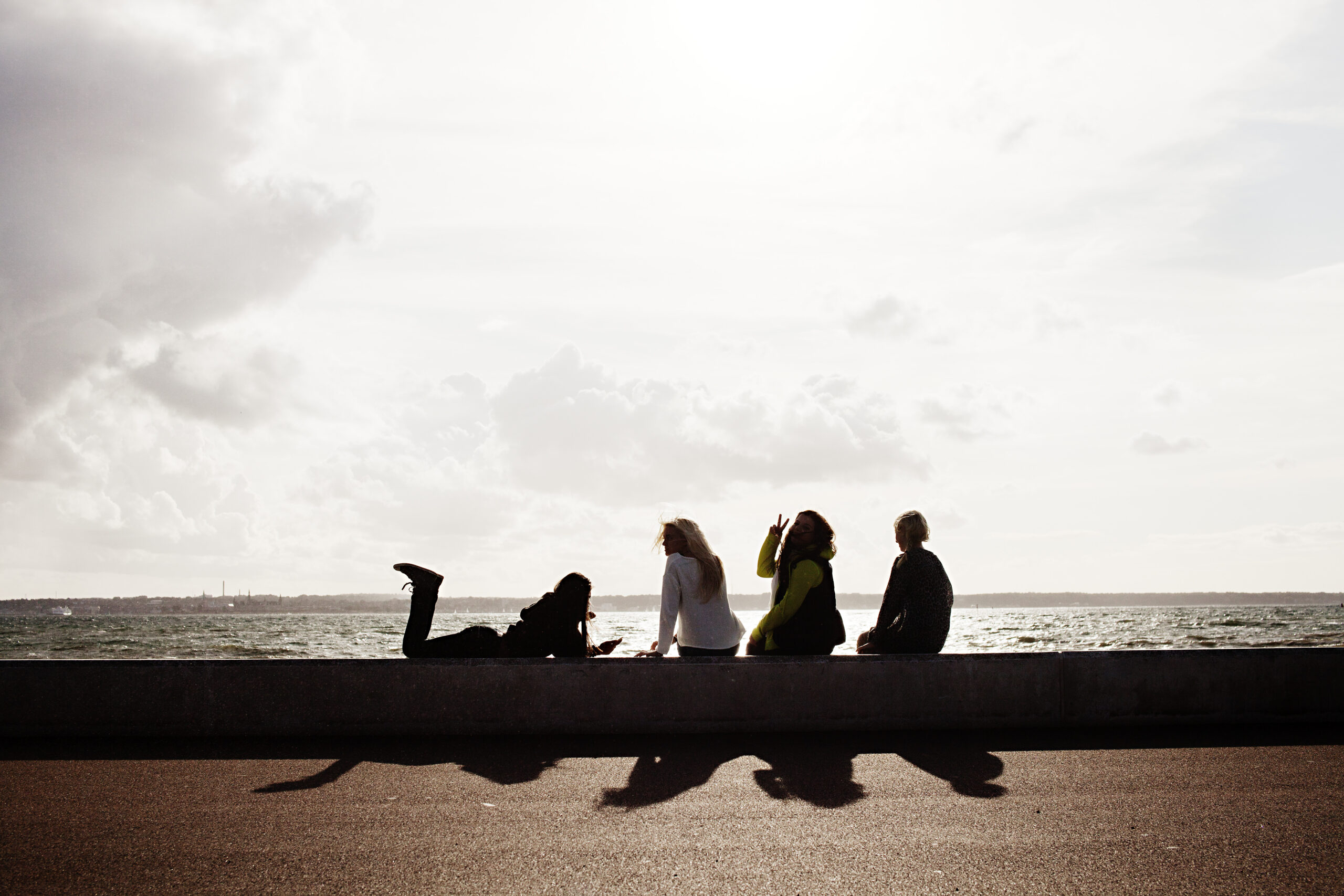 4 ungdomar sitter vid havet i kvällsljus.