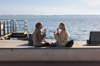 2 unga flickor äter glass vid havet vid gröningen.