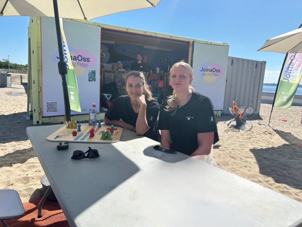 2 tjejer på stranden vid ett bord och ett fia-spel