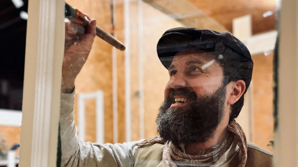 en man med keps och skägg målar i ett hus