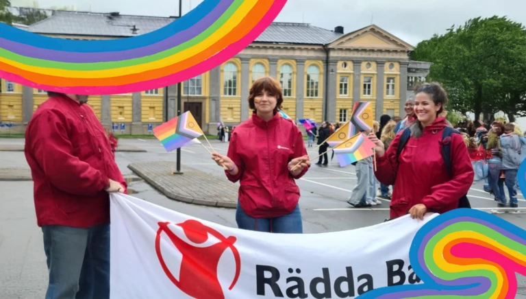 Rädda Barnen deltar i ett pridetåg med flaggor