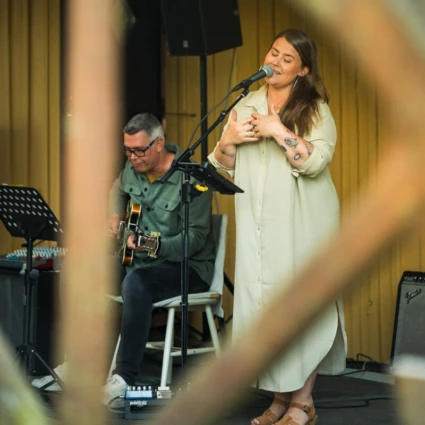 en sångerska och gitarist uppträder på en scen utomhus