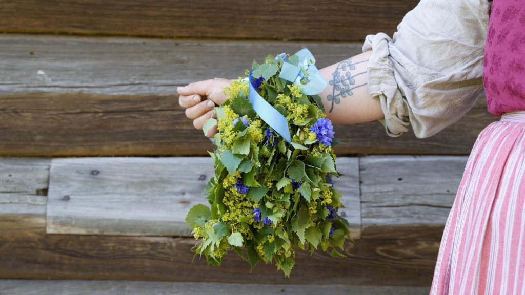 En blomsterkrans som hänger på en arm som tillhör en kvinna i traditionell folkdräkt