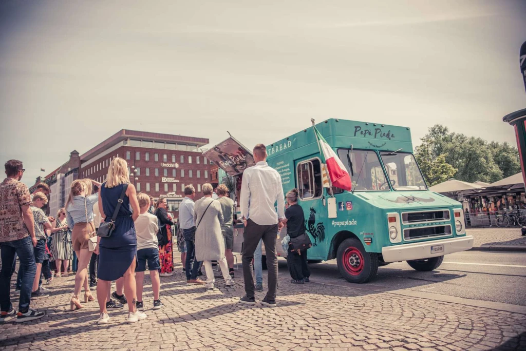 Grön food truck med personer framför i kö för att handla mat