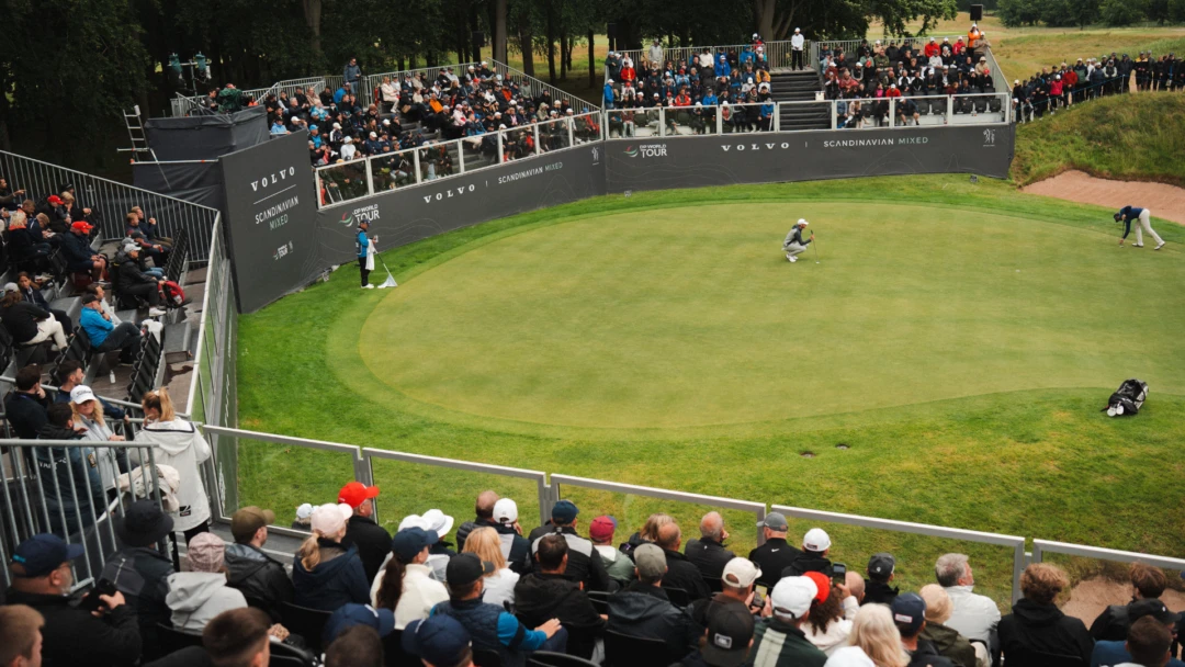 Puttinggreen med en golfspelare och publik på läktare runt om.