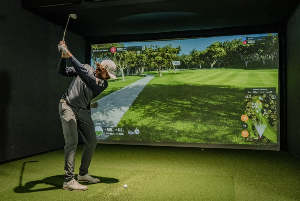 en golfspelare som svingar i ett rum för virtuell golf.