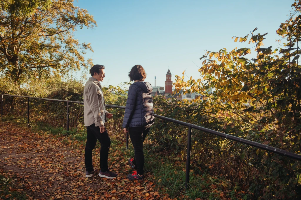 Två personer vandrar längs landborgen med utsikt över staden. Höst.