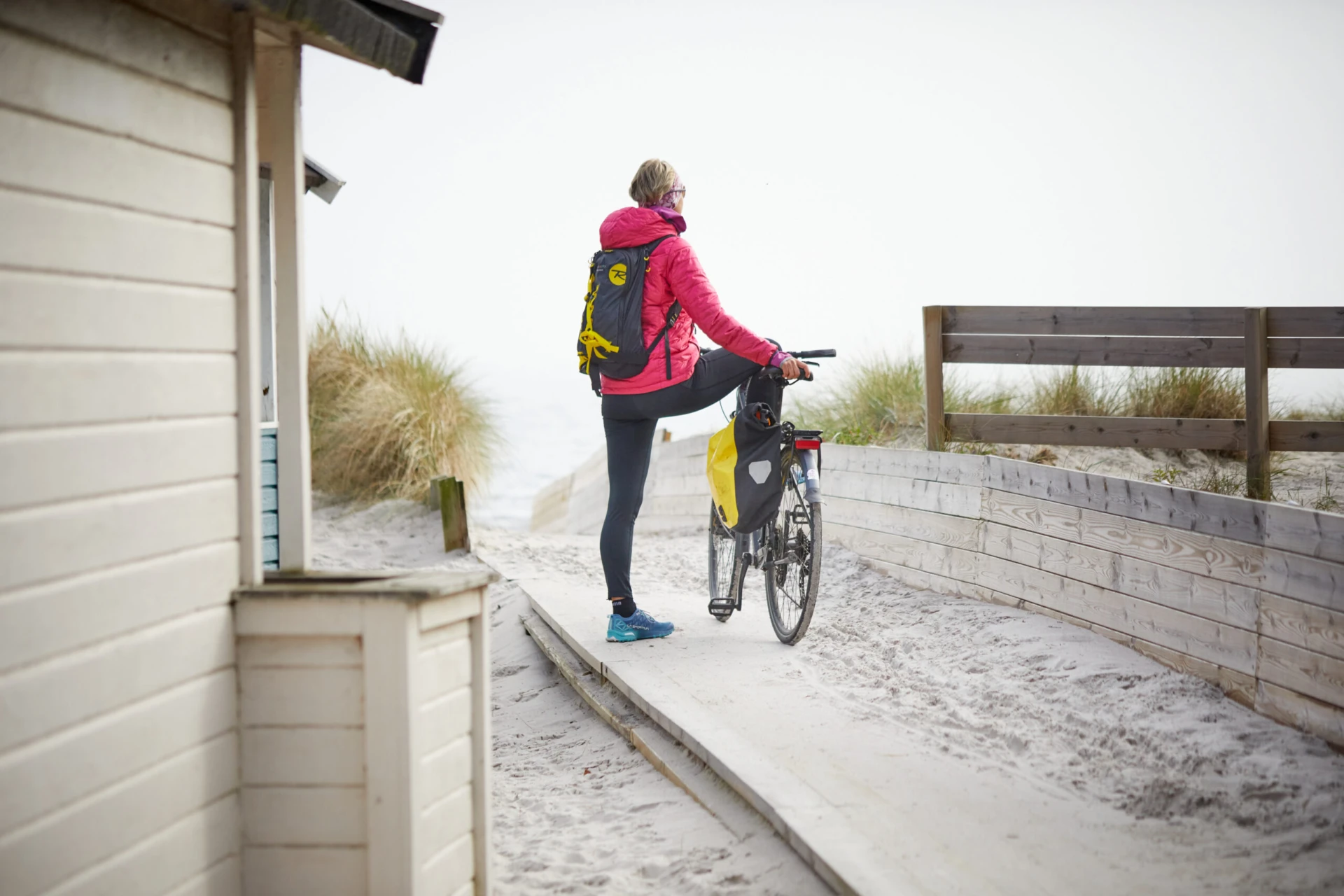 Bild på person bakifrån som står vid sin cykel på en strand