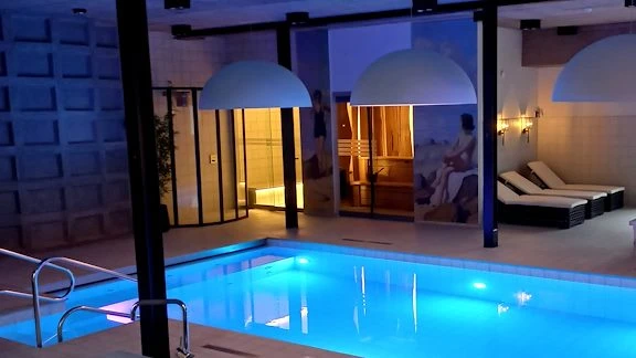 spa pool i dovt ljus med solsängar i bakgrunden och en bastu