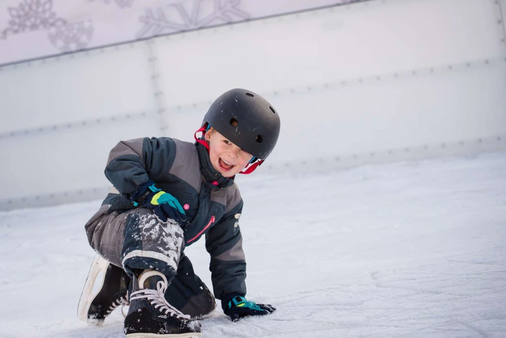 en glad pojke på en isbana med skridskor