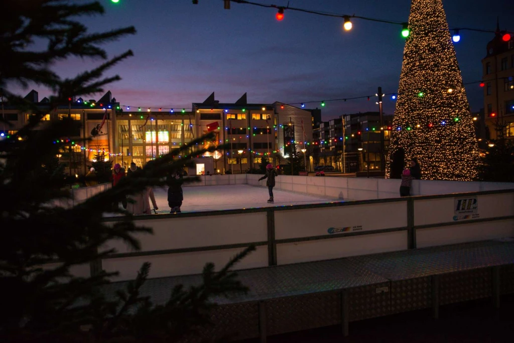 en isbana utomhus med juliga dekorationer i kvällsljus