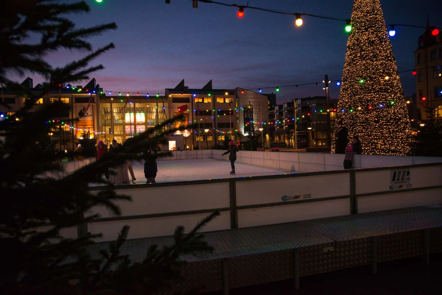 en isbana utomhus med juliga dekorationer i kvällsljus