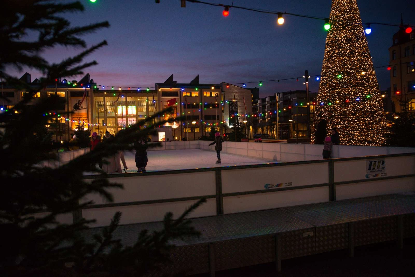 en isbana utomhus med juliga dekorationer i kvällsljus