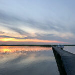 solnedgångsbild över en brygga och en ö