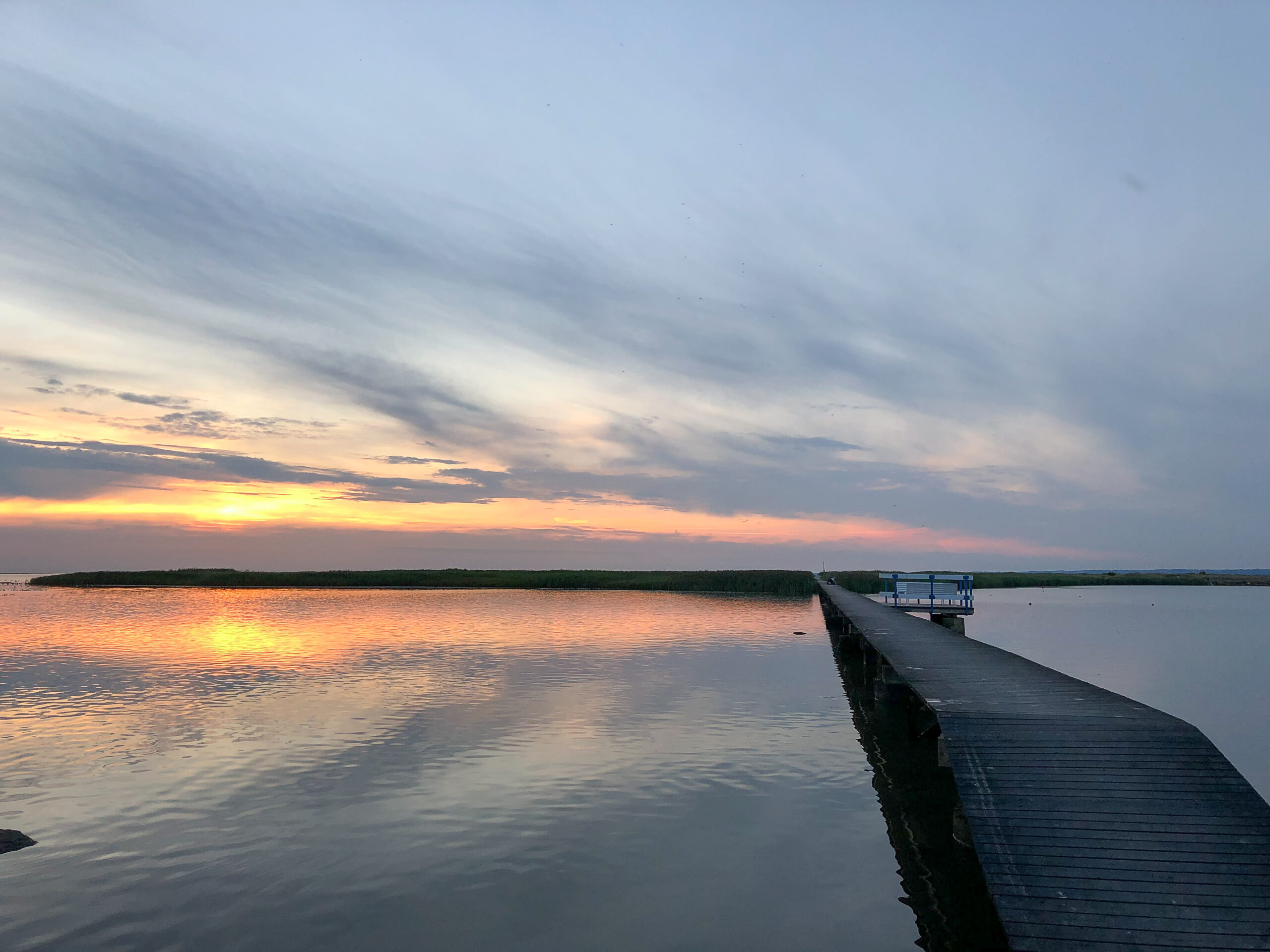 solnedgångsbild över en brygga och en ö
