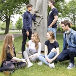 Sex elever ståendes och sittandes framför en staty