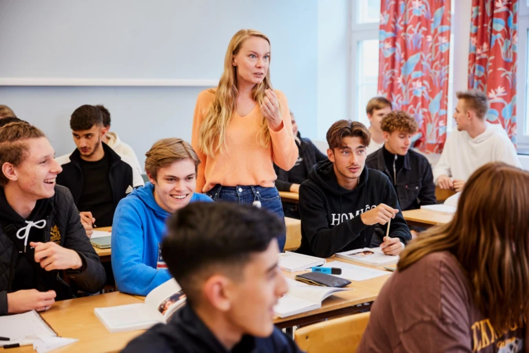 Lärare som står bland elever i ett klassrum.