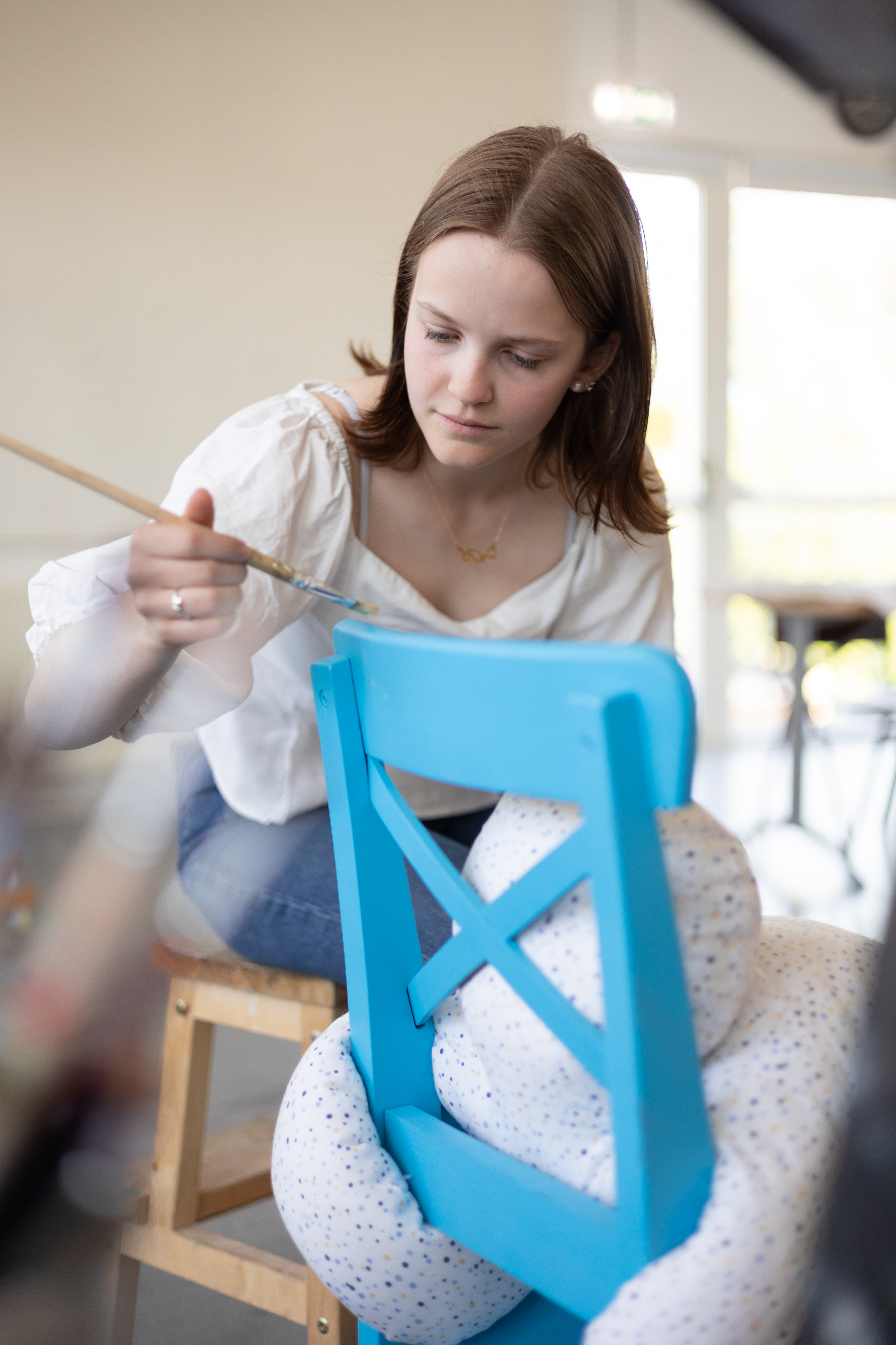 Student in the English speaking school paiting a chair.