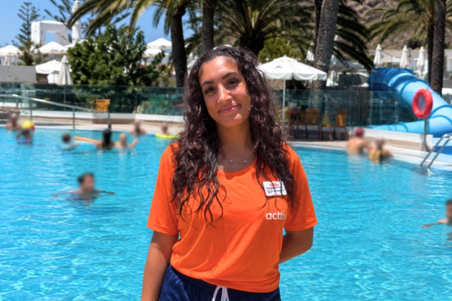 Ung kvinna framför en pool på Gran Canaria där hon jobbar 