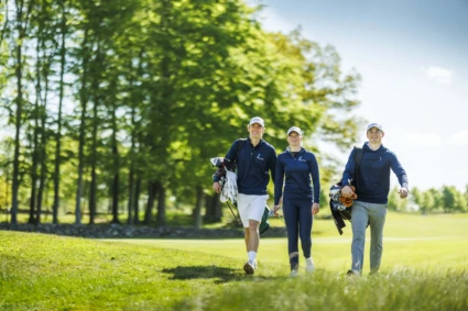 Golfelever som går med sina bagar på golfbanan.