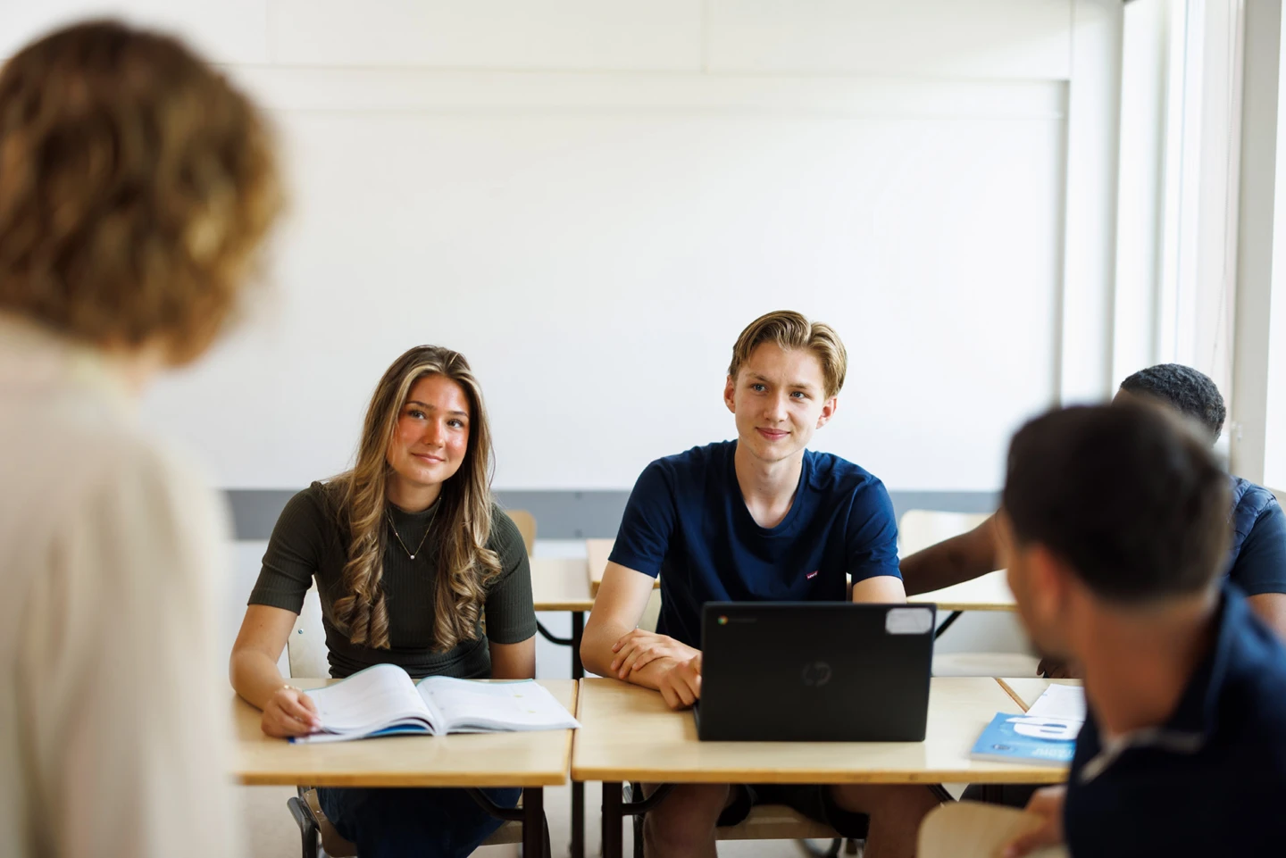 elever sitter i ett klassrum och pratar med sin lärare