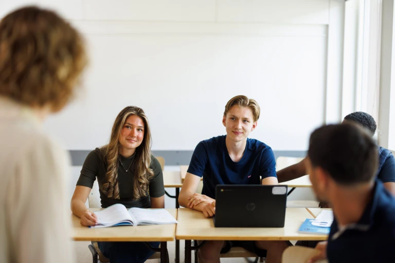 elever sitter i ett klassrum och pratar med sin lärare
