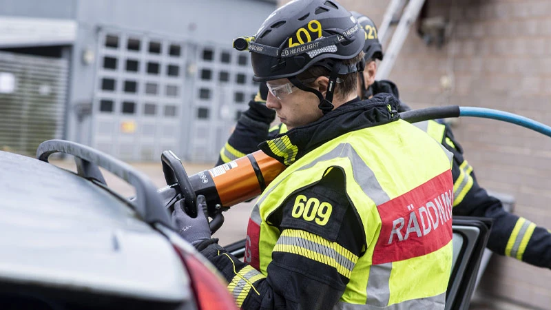 Brandman som klipper i en bil vid en trafikolycka
