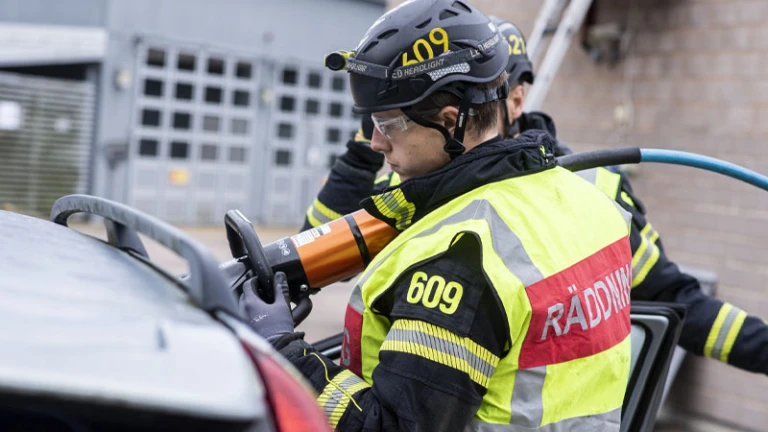 Brandman som klipper i en bil vid en trafikolycka
